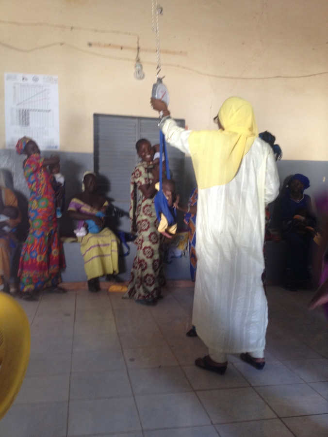 The head nurse, Maimouna, weighing a baby before the vaccinations